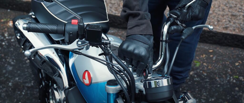 Eine Hand steckt den Schlüssel in das Zündschloss eines Honda Monkey 125 Motorrads