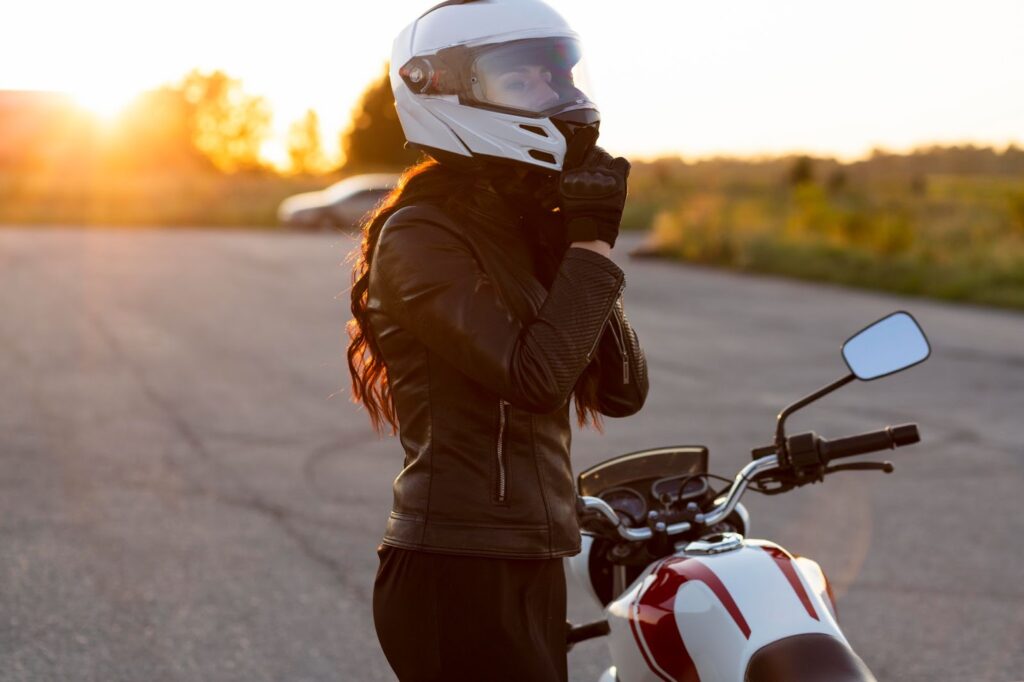 Frau nimmt neben dem Motorrad ihren Helm ab